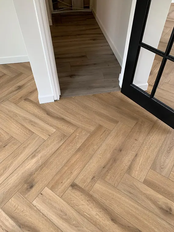 Warme eiken visgraat PVC-vloer met zwarte stalen taatsdeur